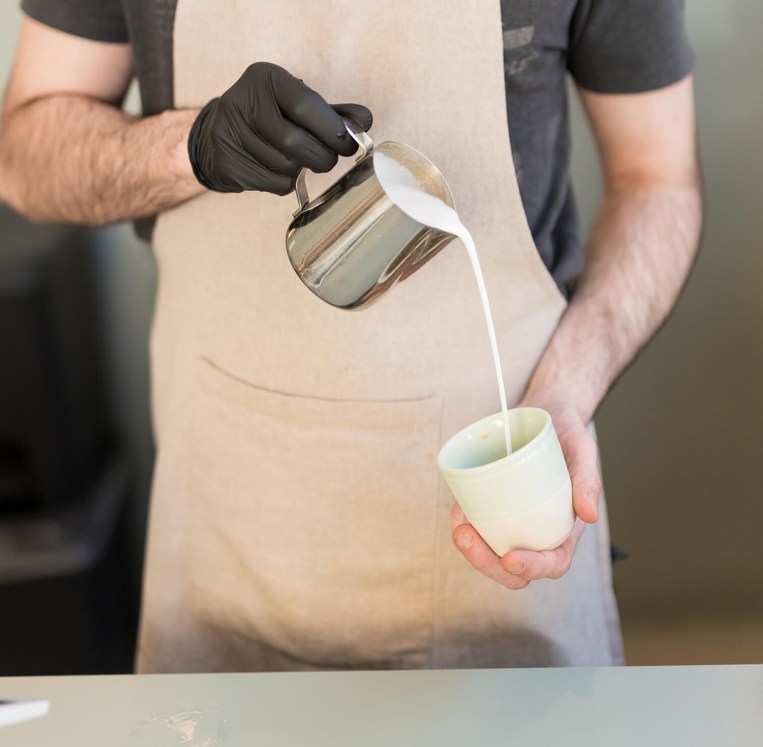 Barista pouring milk into an N1 ceramic cup